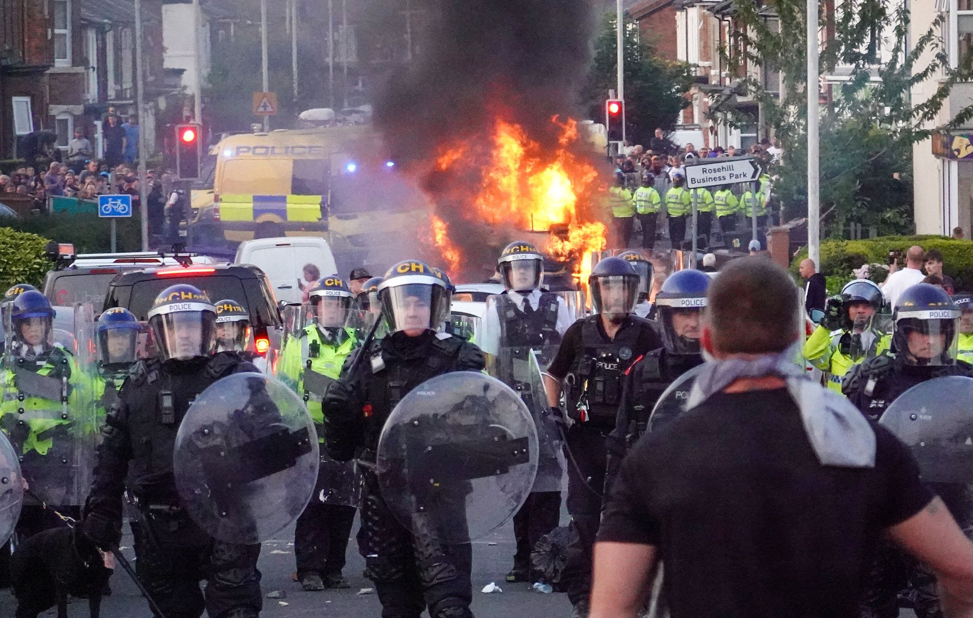 Riot police hold back protesters near a burning police vehicle on July 30, 2024 in Southport, England.