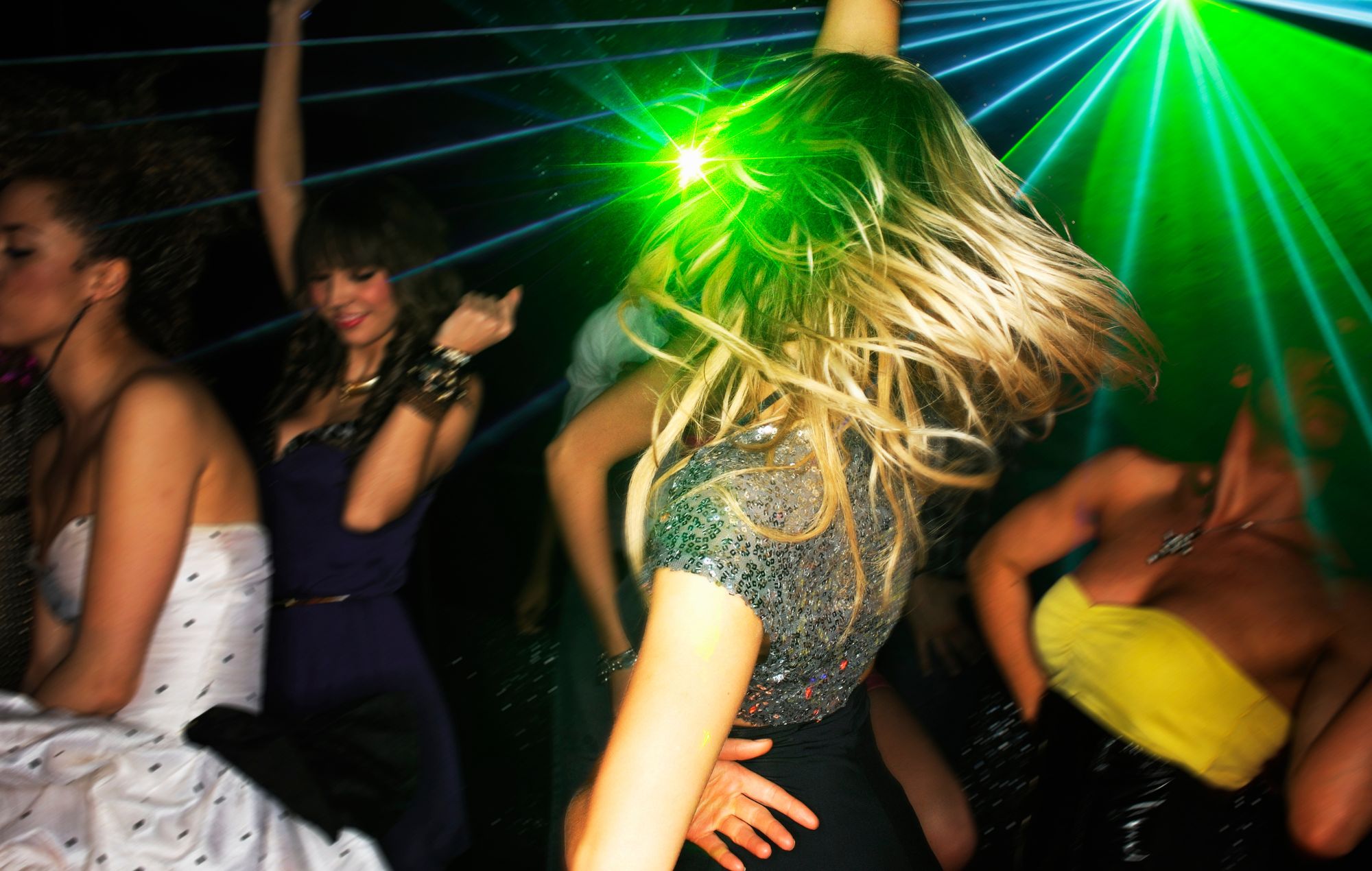 Group of young people dancing in nightclub with laser lighting.